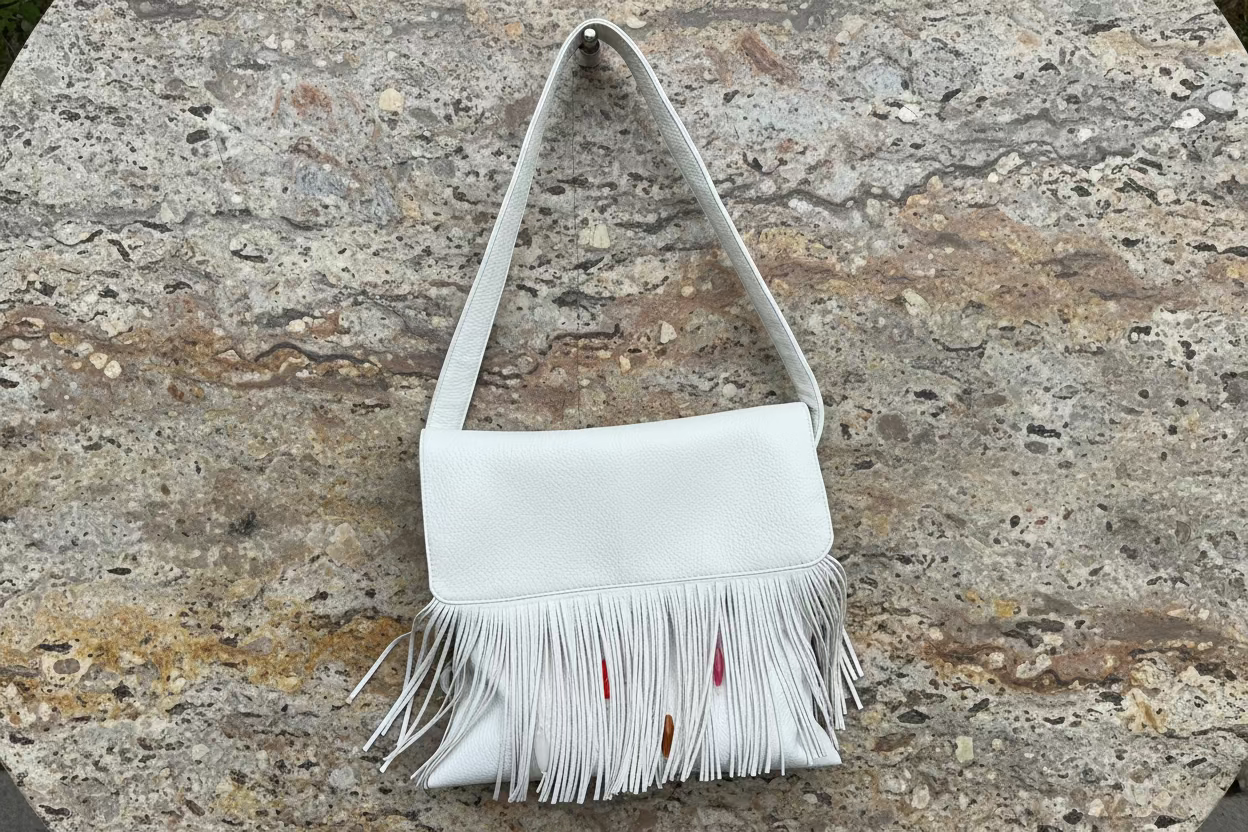 White handbag with fringe on a stone surface