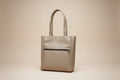Beige handbag on a car seat with a visible brand logo.