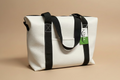 White tote bag with black straps on a dark fabric background