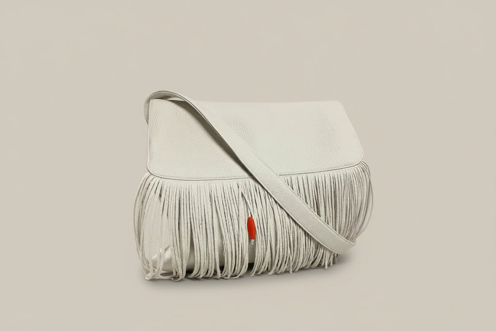 White handbag with fringe on a rock by a mountain stream