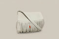 White handbag with fringe on a rock by a mountain stream