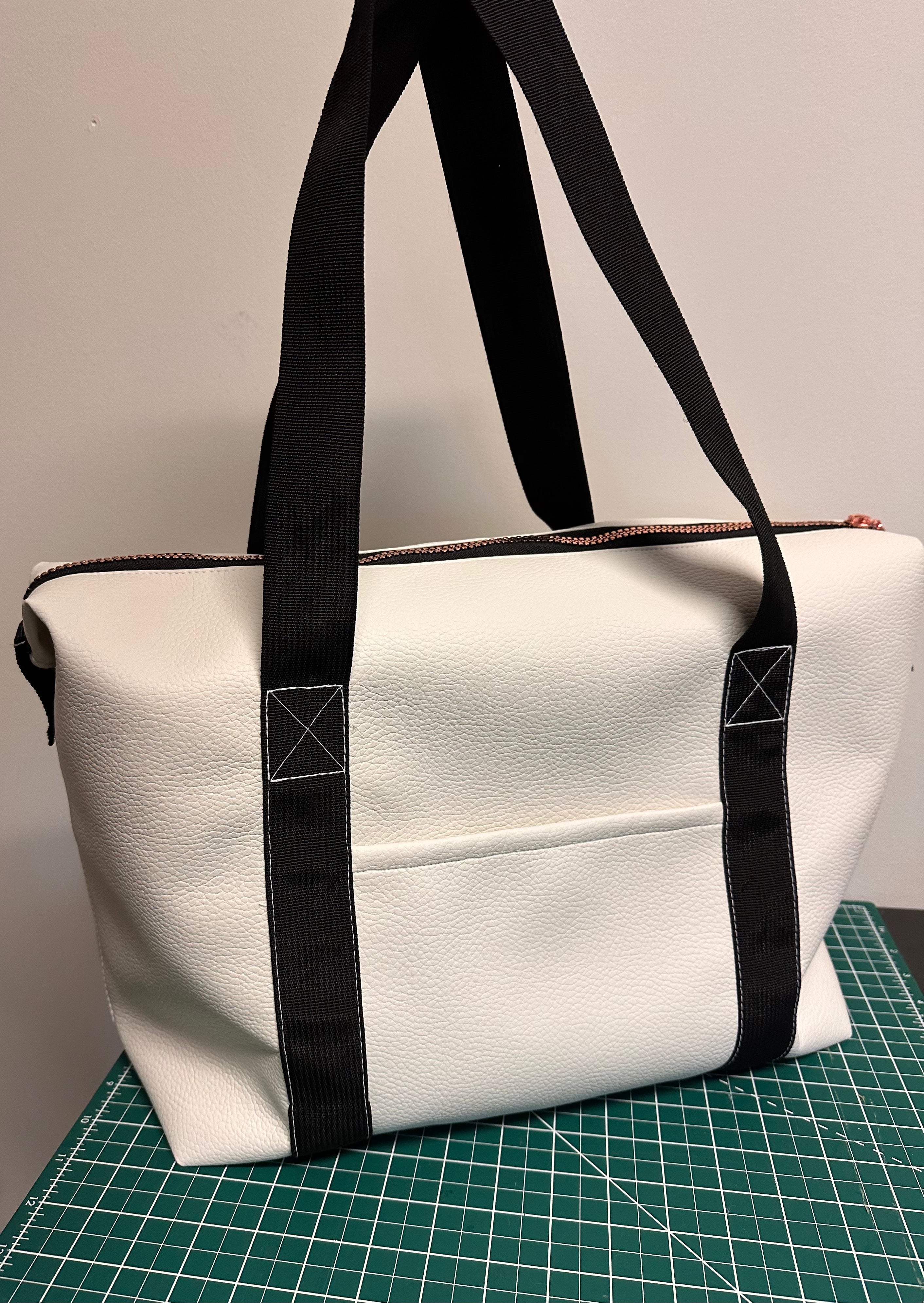 White bag with black straps on a green cutting mat