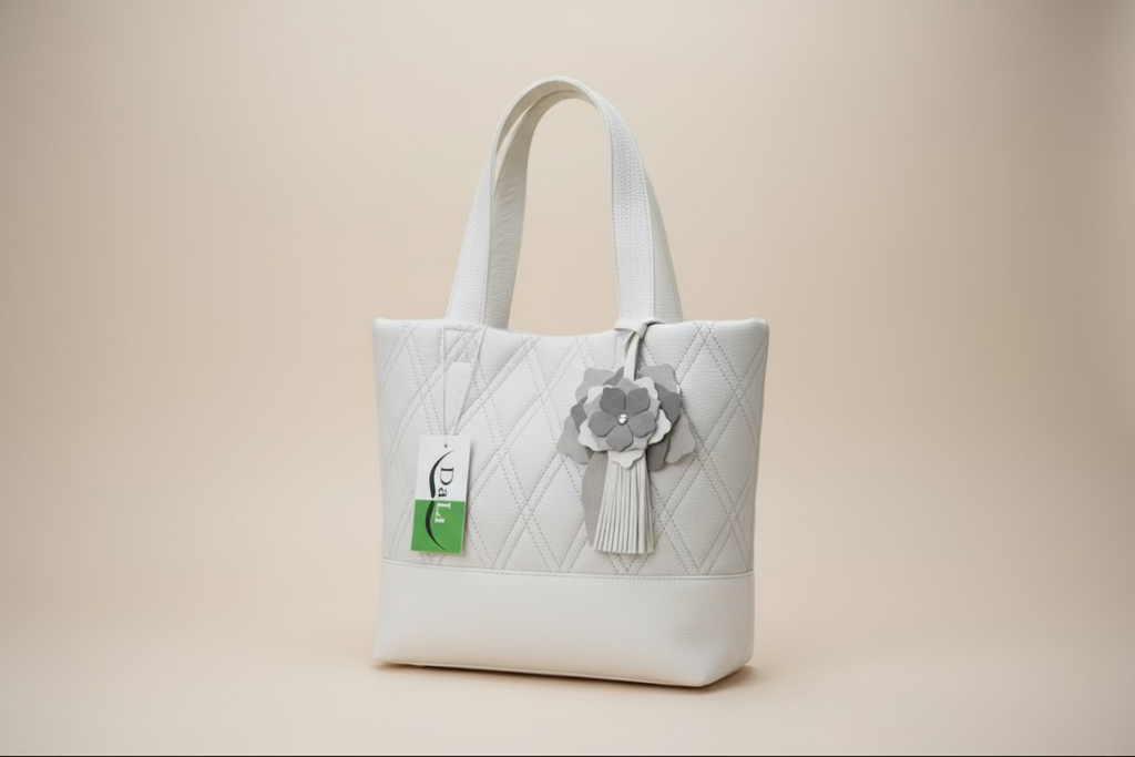 Quilted pattern handbag with a decorative flower and tag on grass