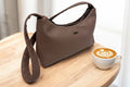 Brown faux leather handbag on a wooden surface with a neutral background