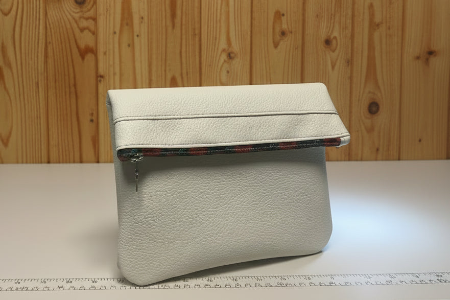 Light gray cosmetic bag on a white surface with a wooden background