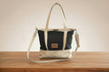 Two-toned handbag with black and beige design on a wooden surface.