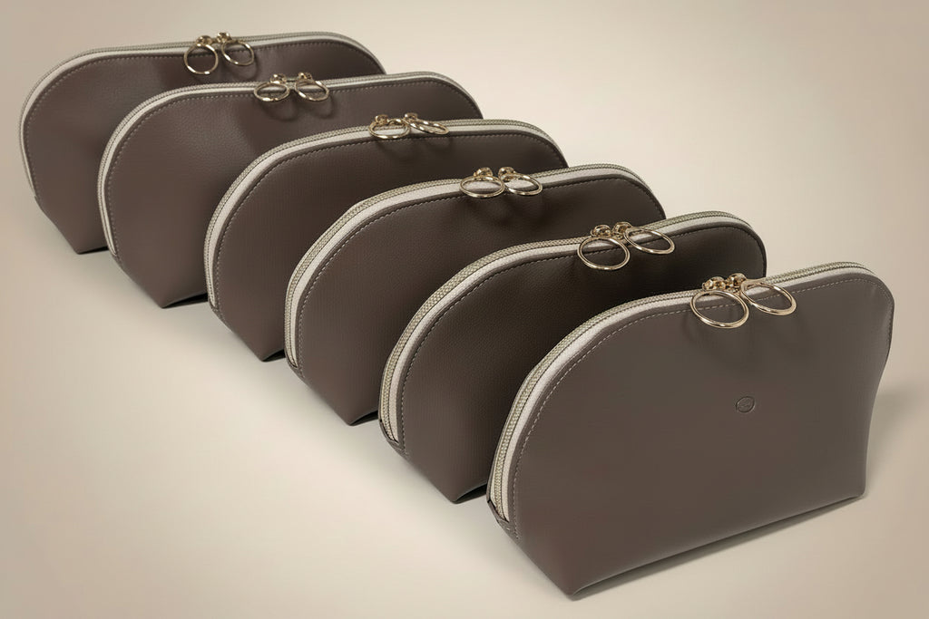 Set of brown cosmetic bags with silver zippers on a white surface.