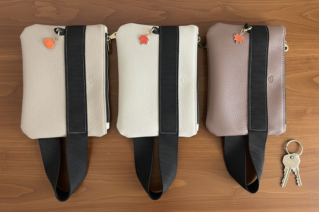 Three wrist bags with black straps on a wooden surface, with keys beside them.