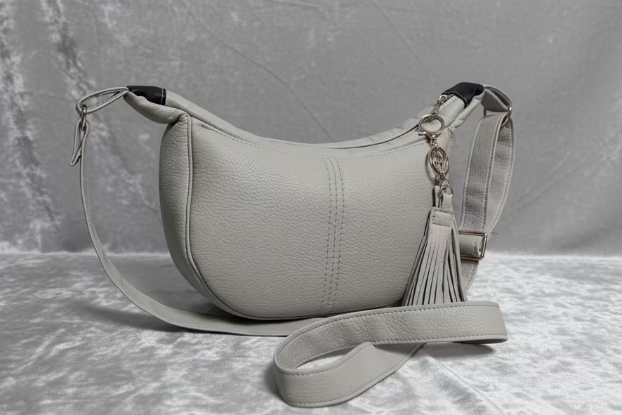 Light Grey handbag with a tassel on a textured surface