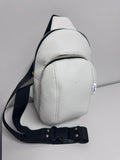 White leather sling bag with black strap on a light gray background