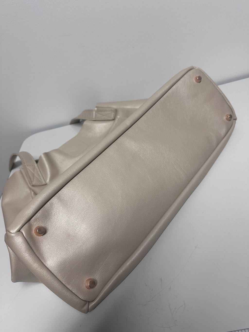 Beige genuine leather bag with metal feet on a white background