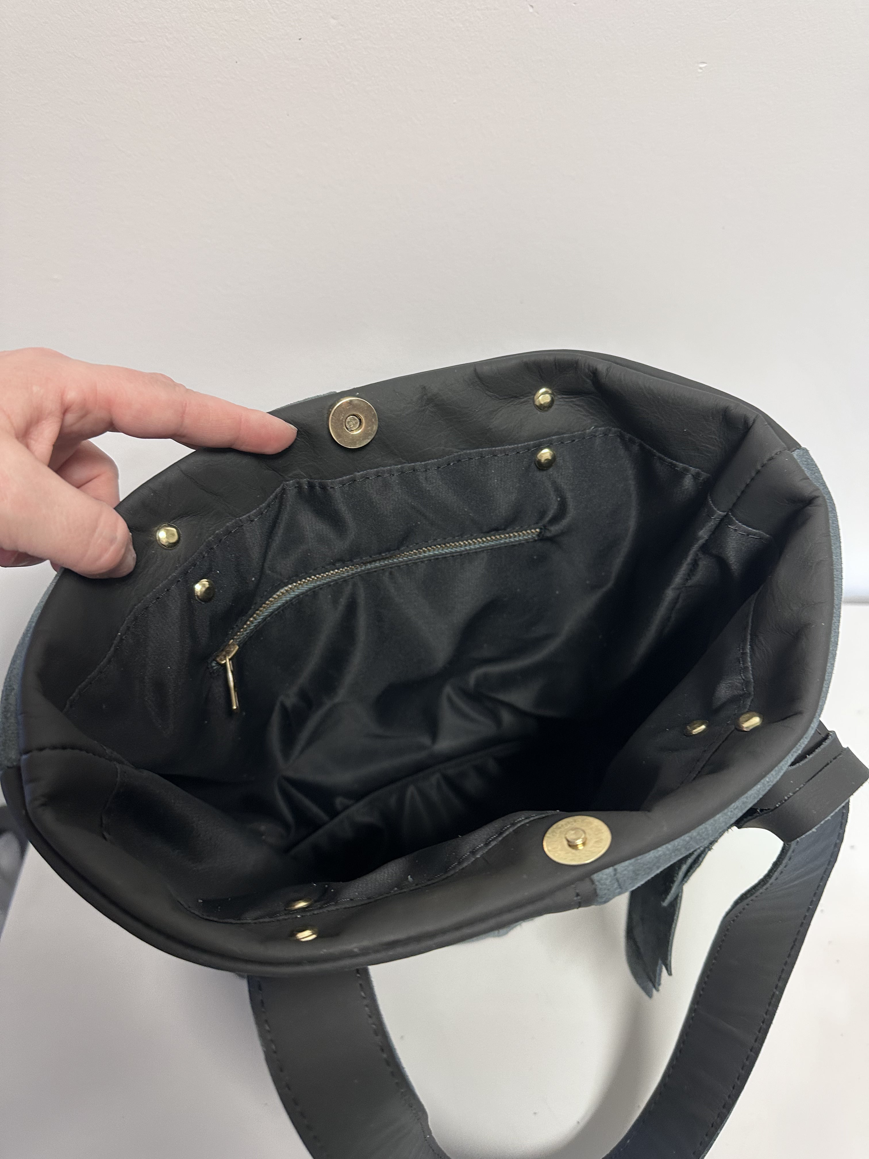 Black handbag with gold buttons on a white background