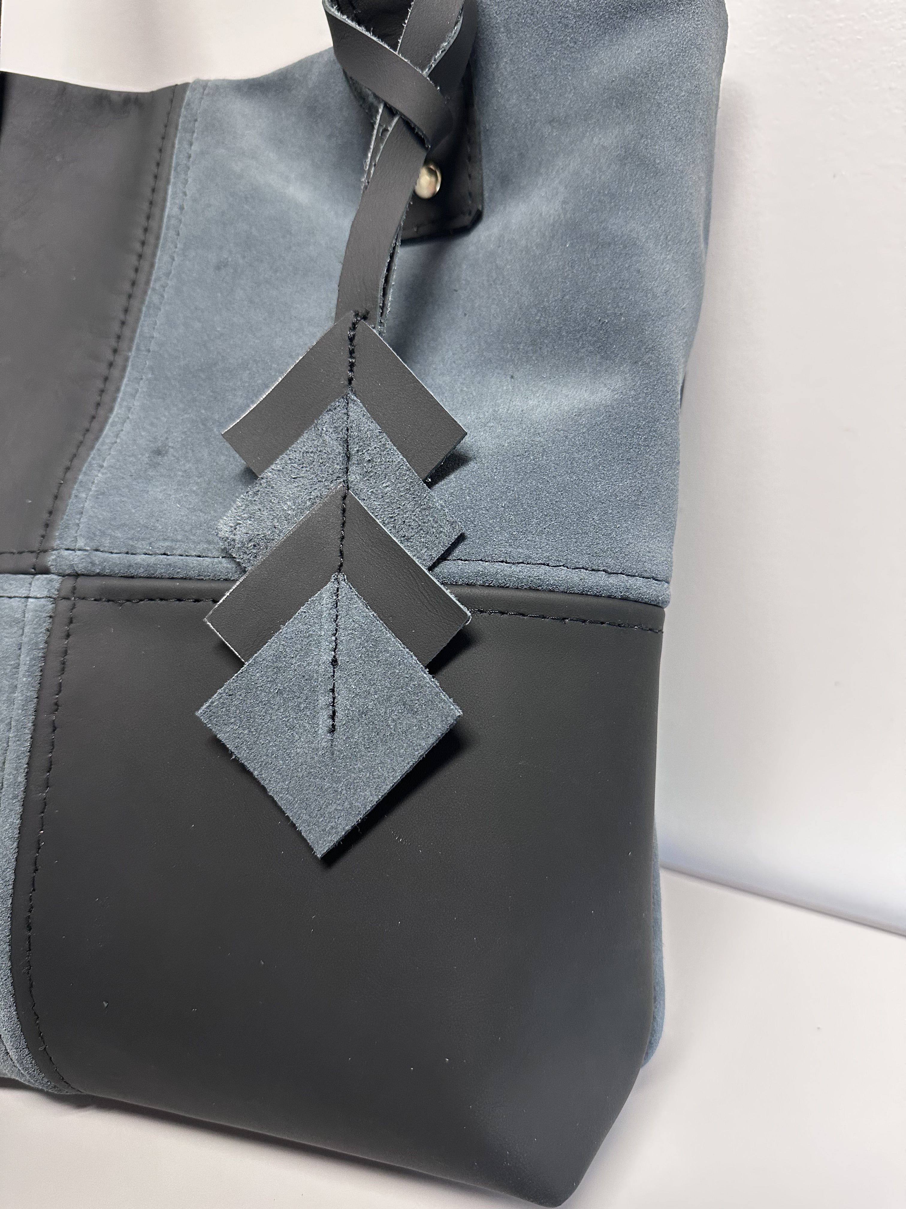 Gray handbag with decorative suede leather strap on a light background