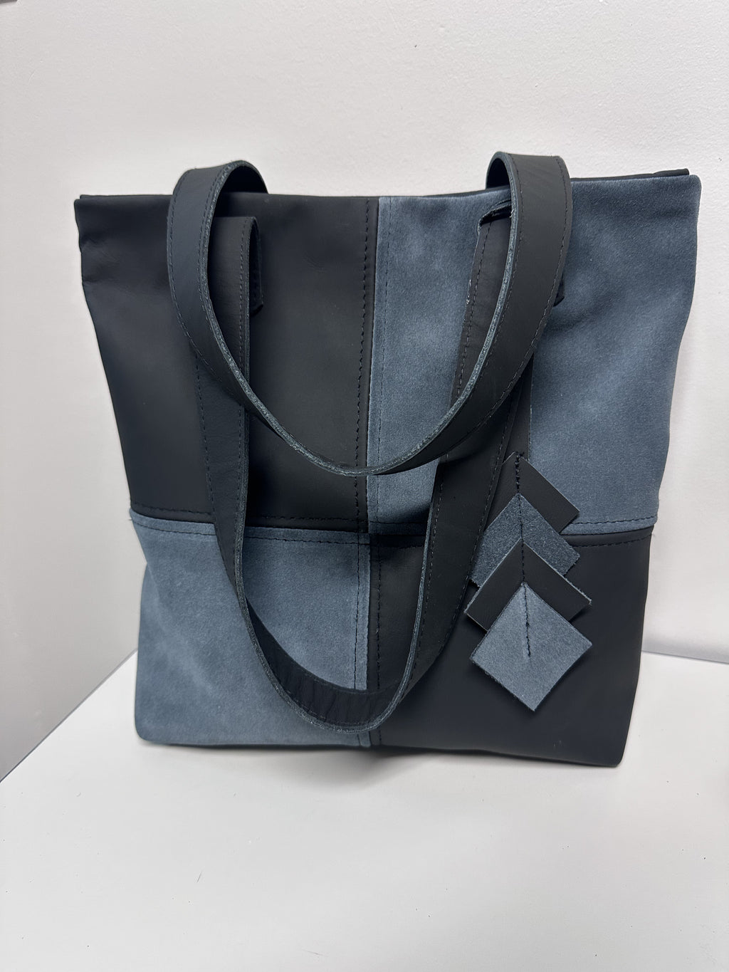 Two-toned blue and black tote bag on a white surface with a light gray background
