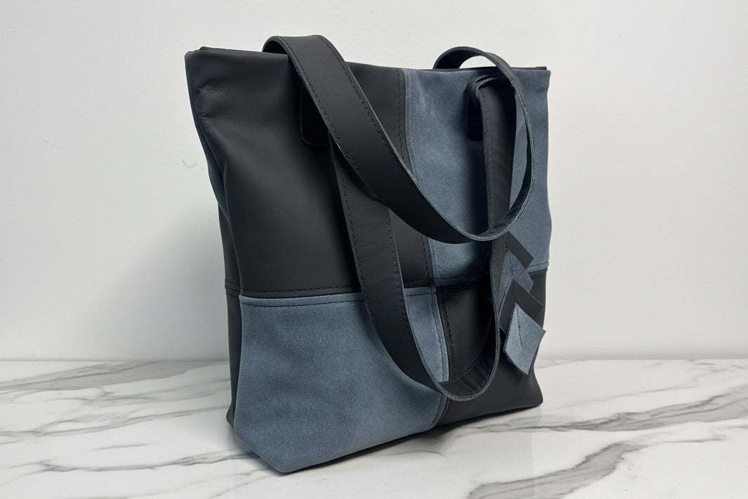Two-toned black and gray tote bag on a marble surface with a light gray background