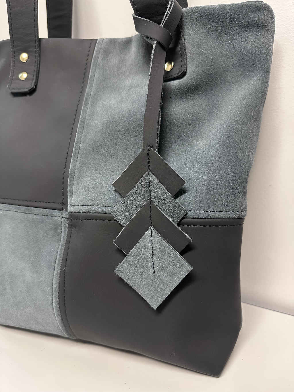 Gray handbag with decorative straps on a light background