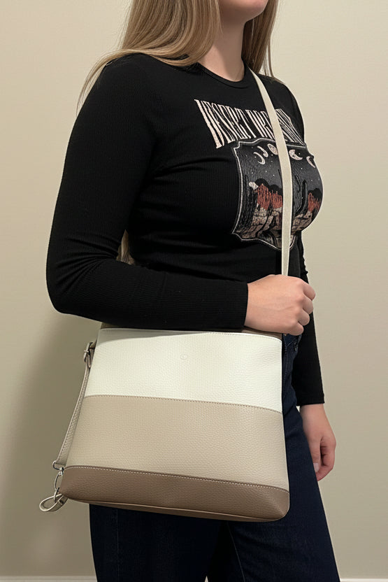 Girl standing with a beige white and brown bag on her shoulder