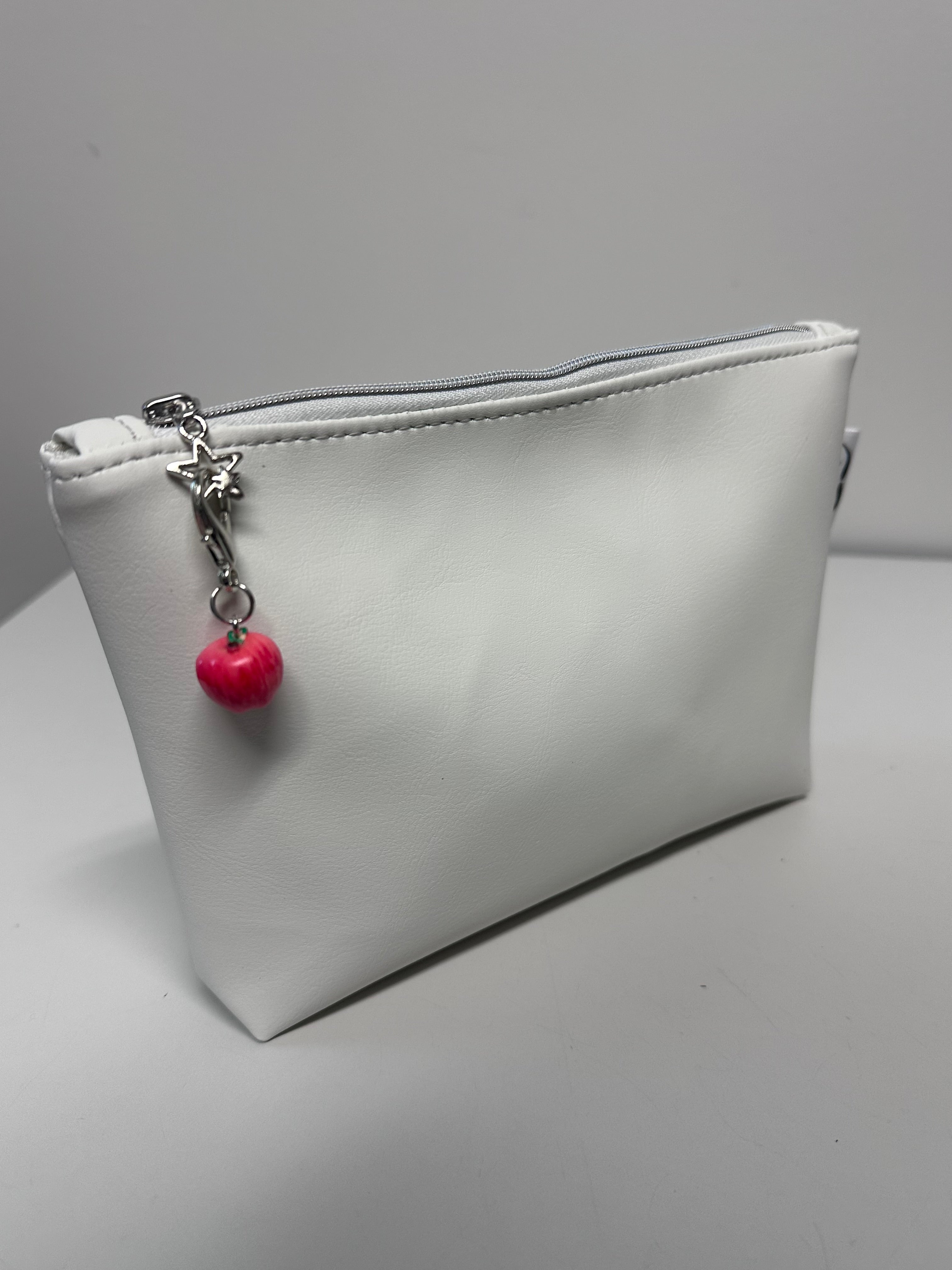 Gray pouch with a red charm on a light gray background