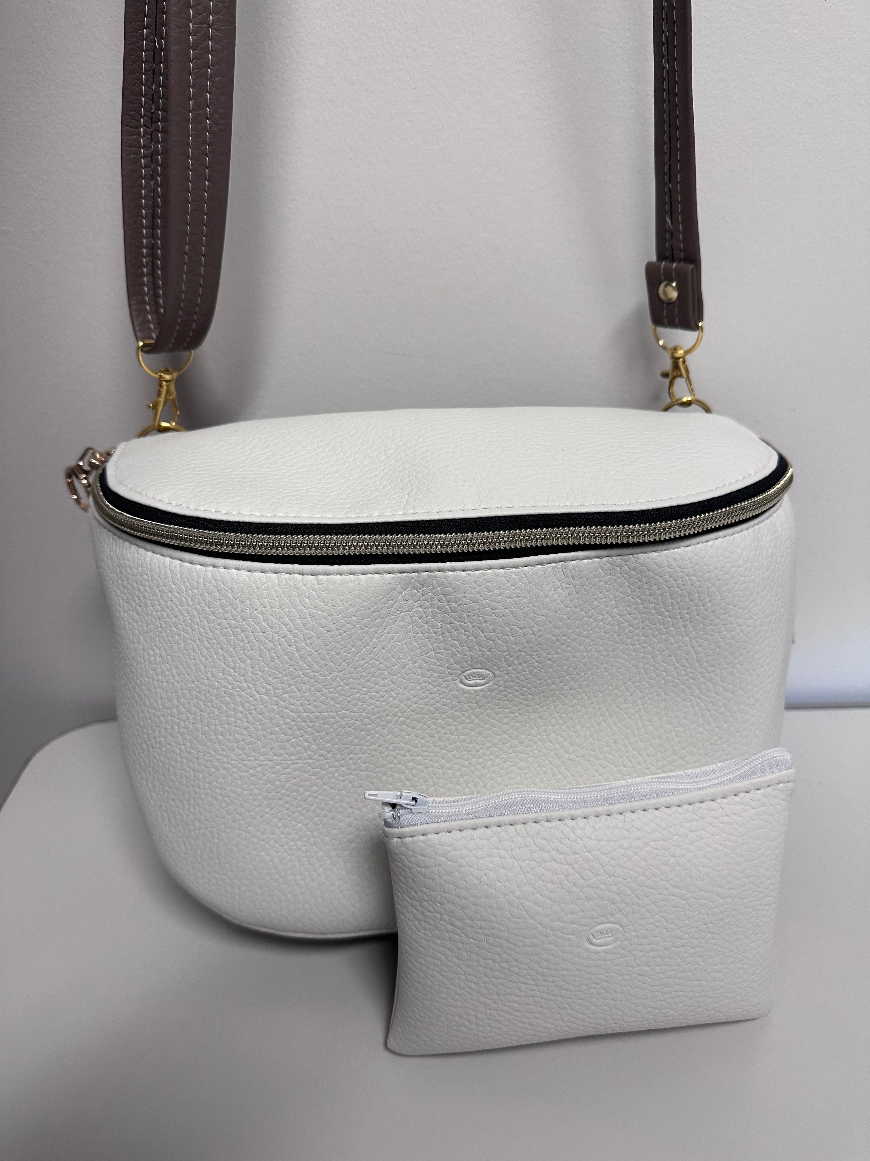 White faux leather handbag with gold zipper on a light gray background