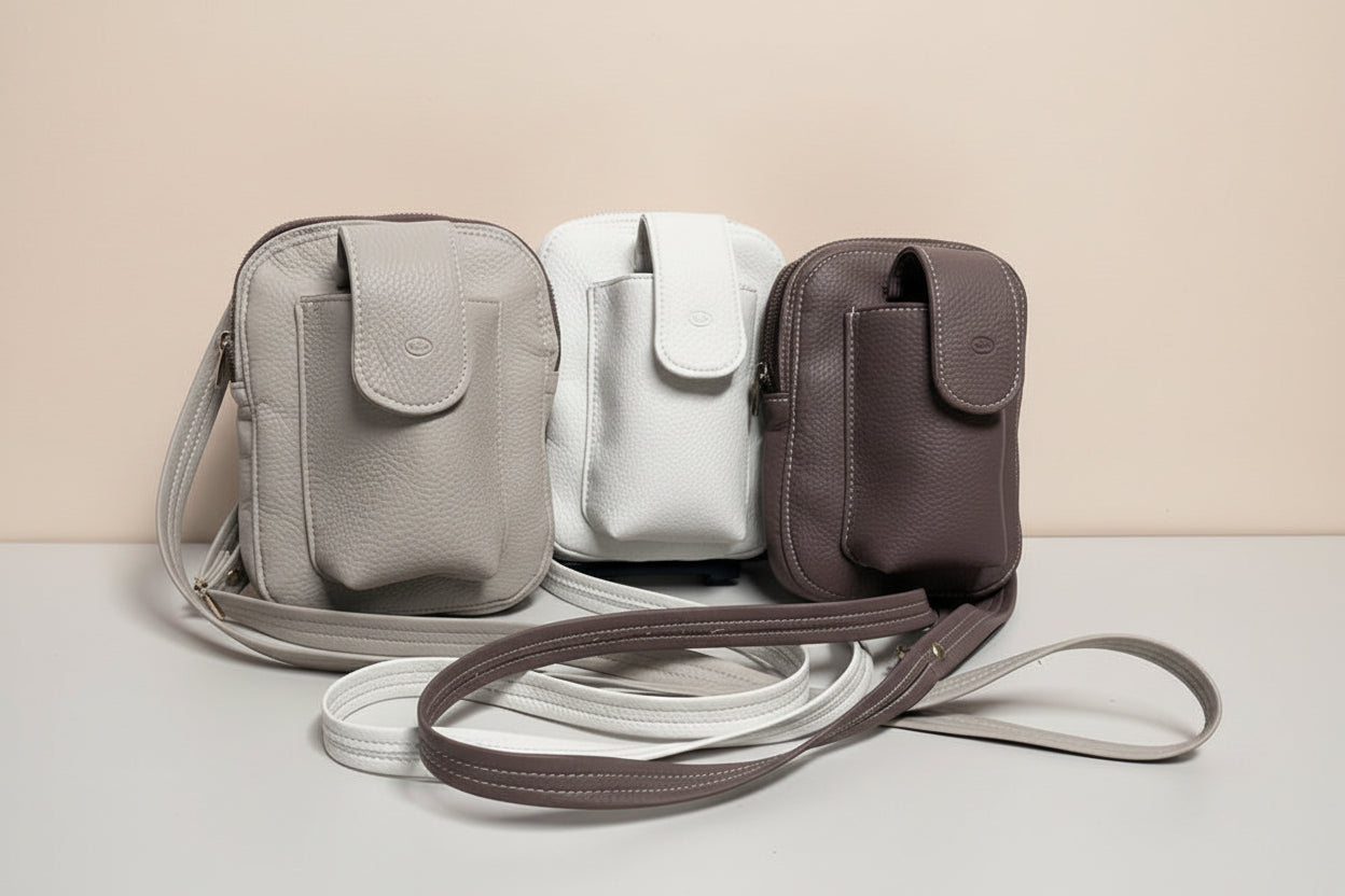 Gray crossbody bag with a brown strap on a light gray background