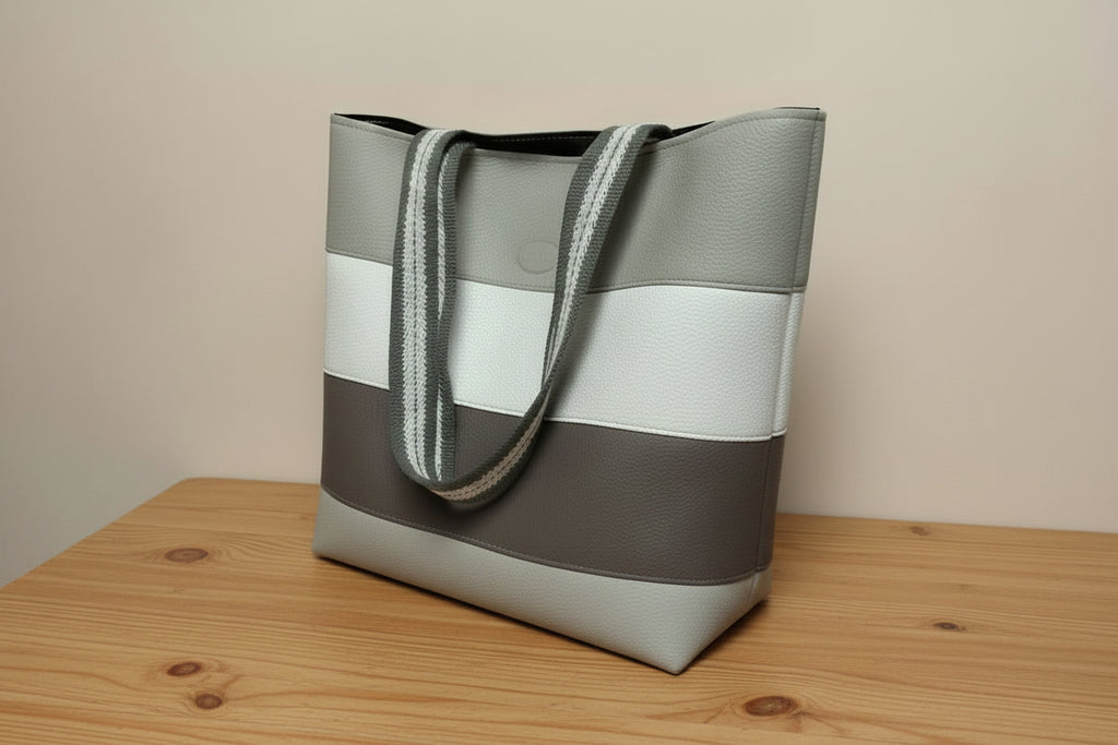 Handbag with a striped handle on a light gray background