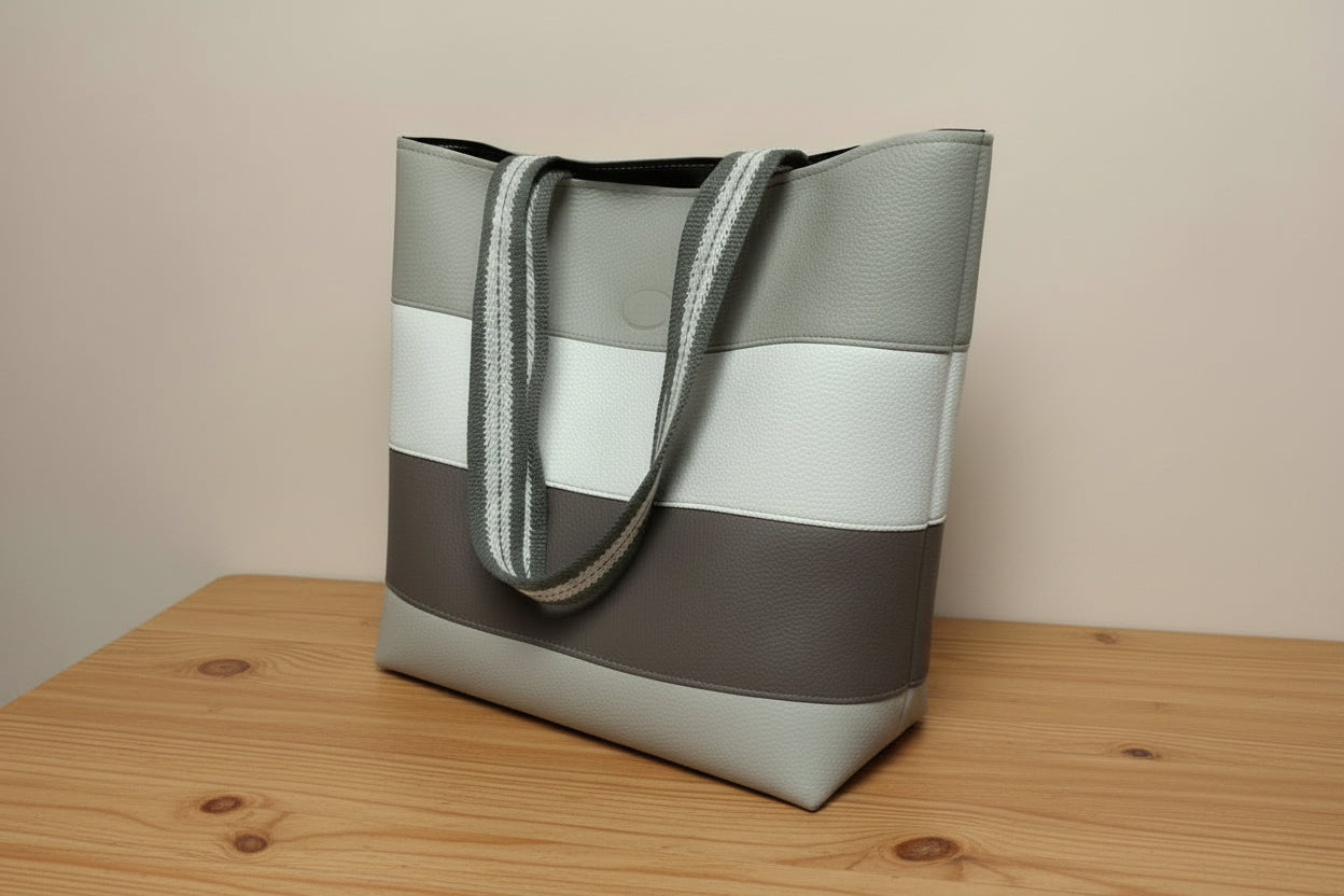 Handbag with a striped handle on a light gray background