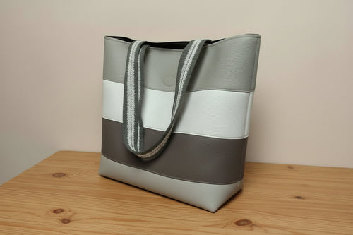 Handbag with a striped handle on a light gray background