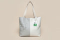 Gray tote bag with a logo, water bottle, and tablet on a gray surface