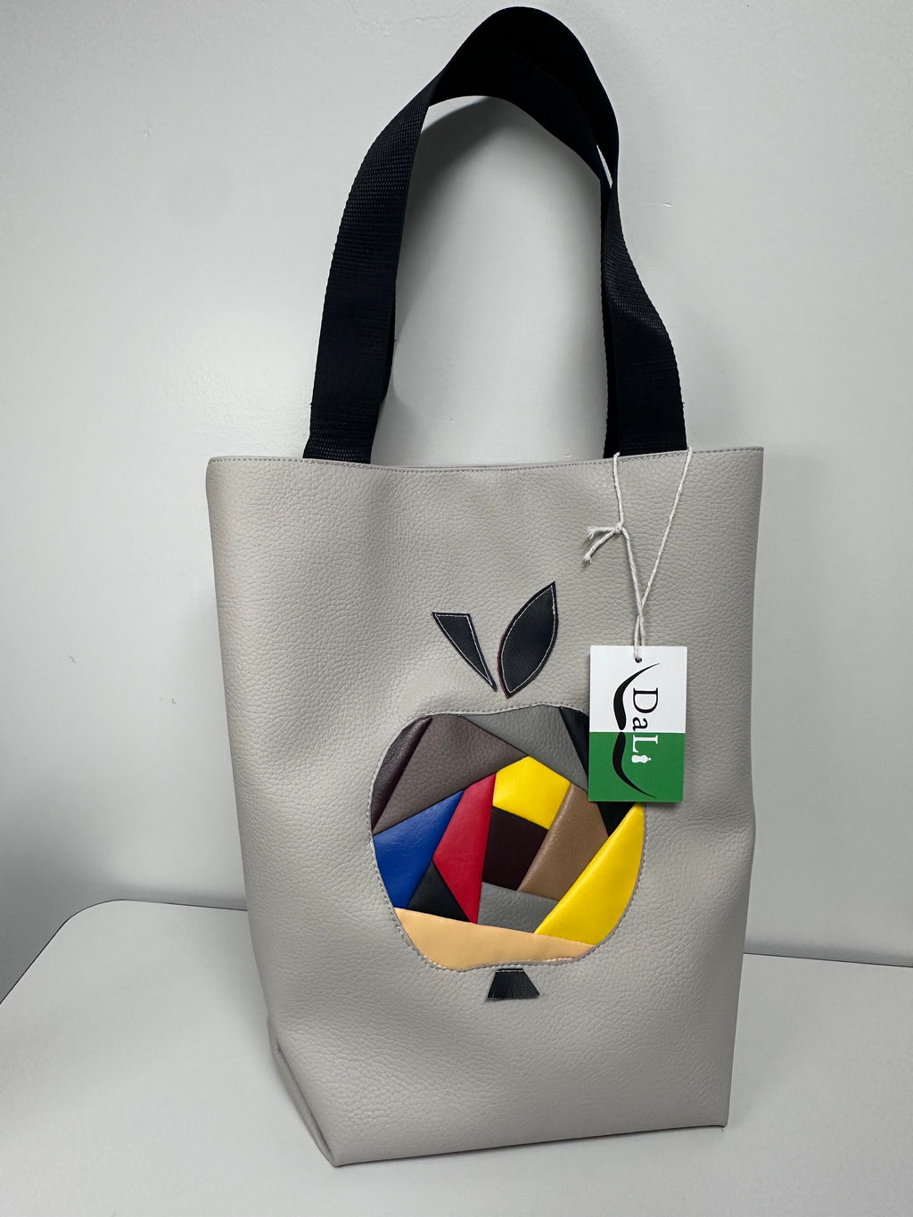 Gray clutch bag with colorful abstract design and brand tag on a light gray background