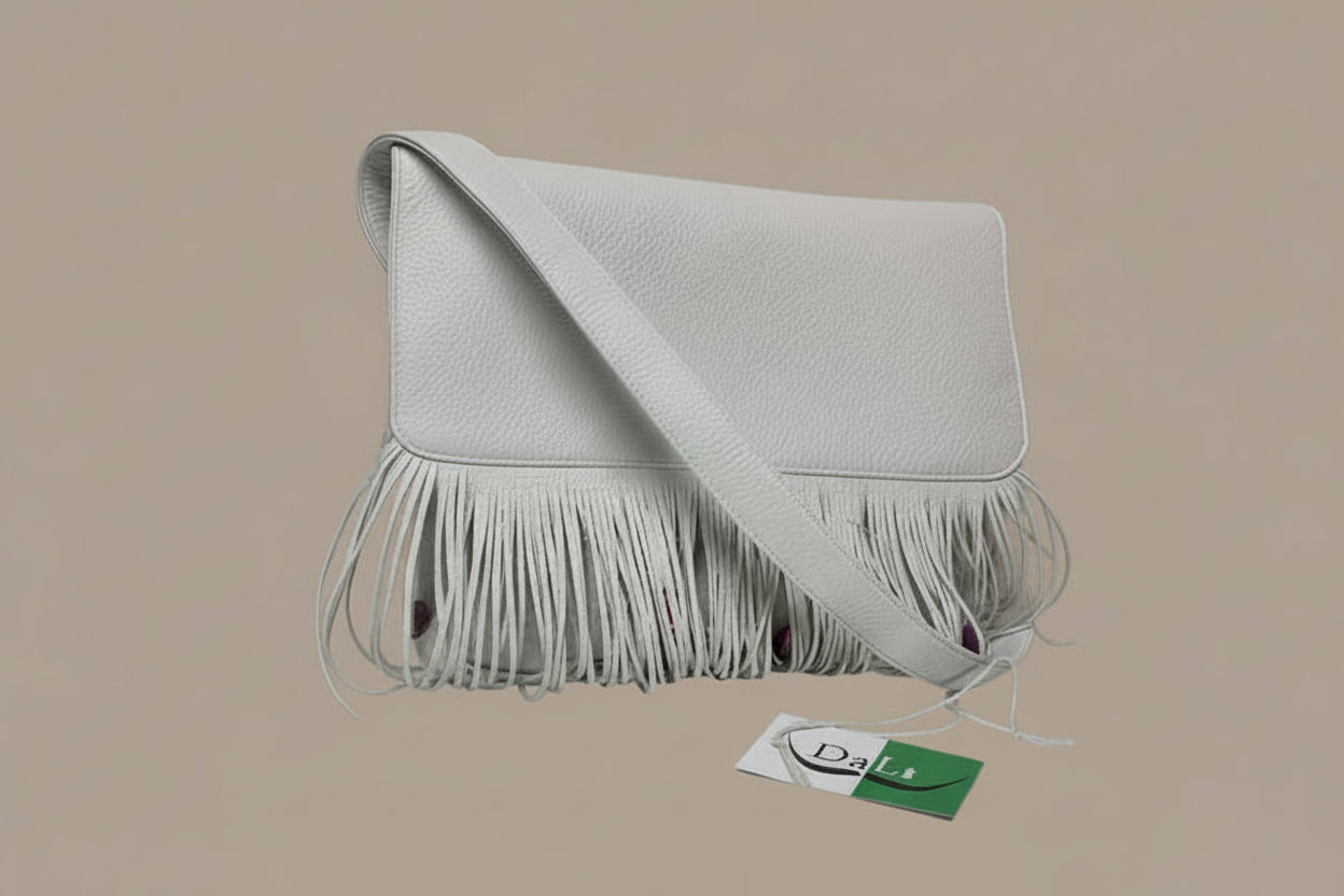 White handbag with fringe details on a reflective surface with a gray background