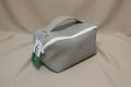 Gray pouch with a white zipper on a light gray background, featuring a Dali tag.