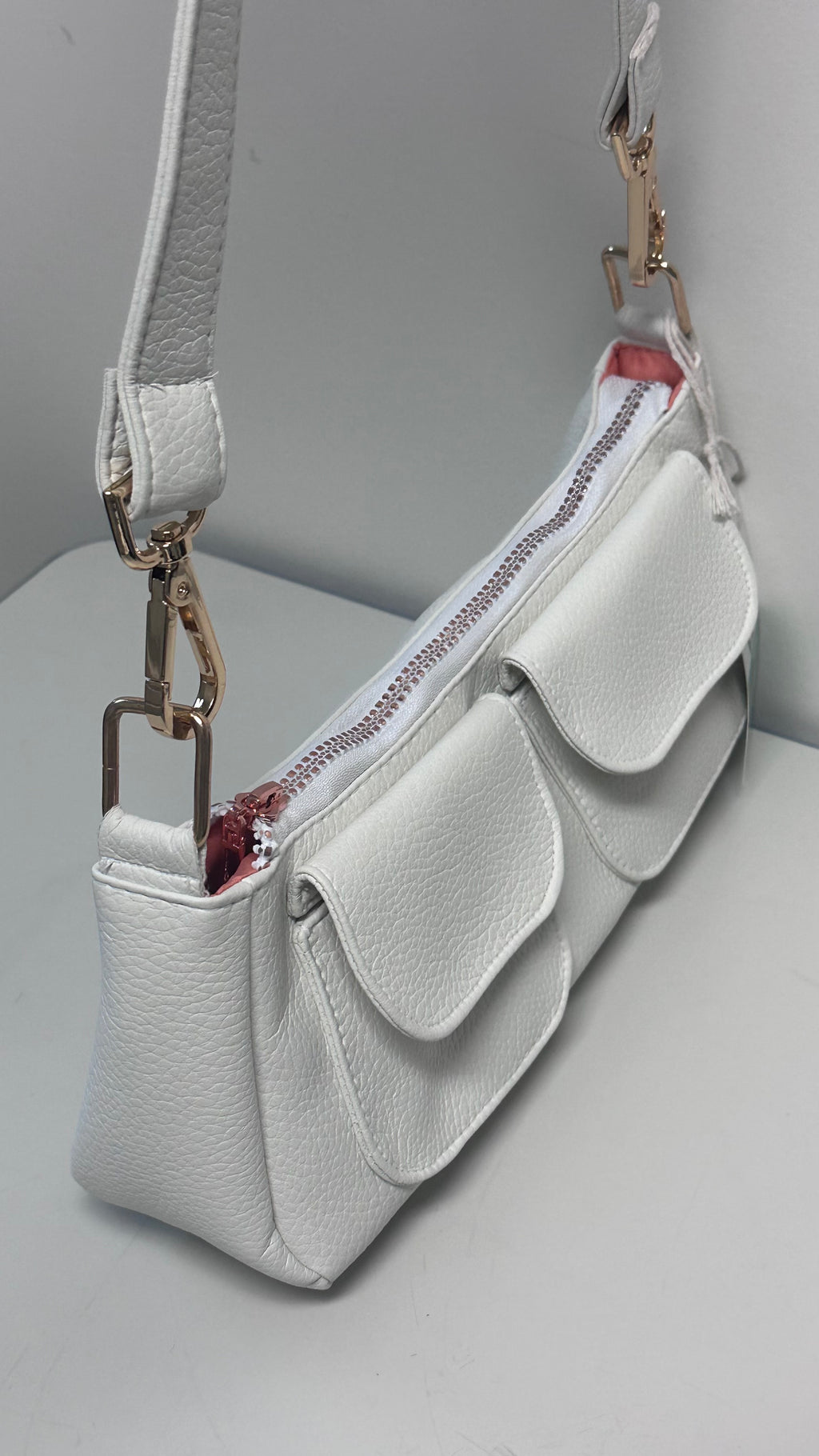 White handbag with a strap on a gray background