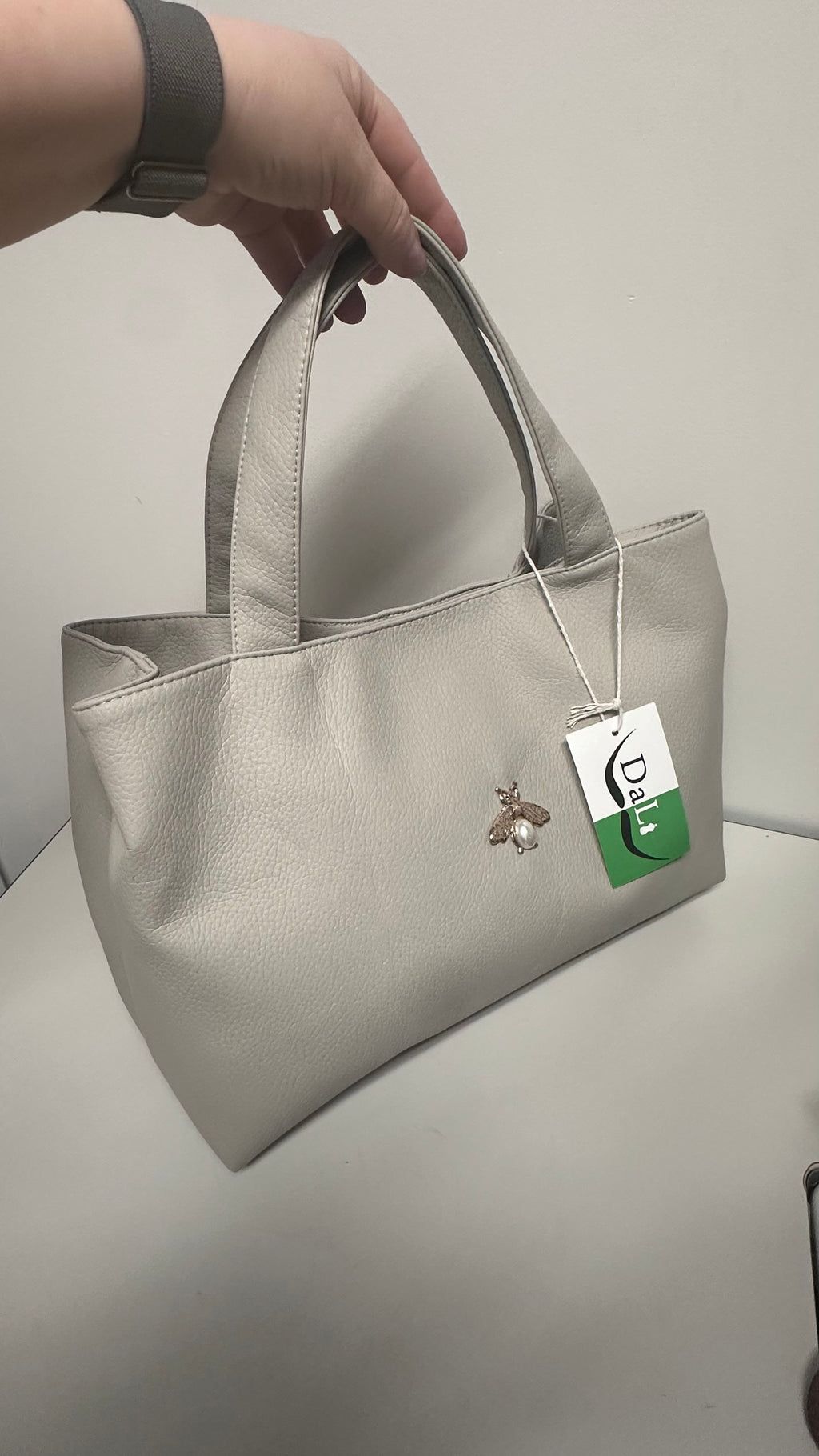 Beige handbag with a brand tag on a light gray background
