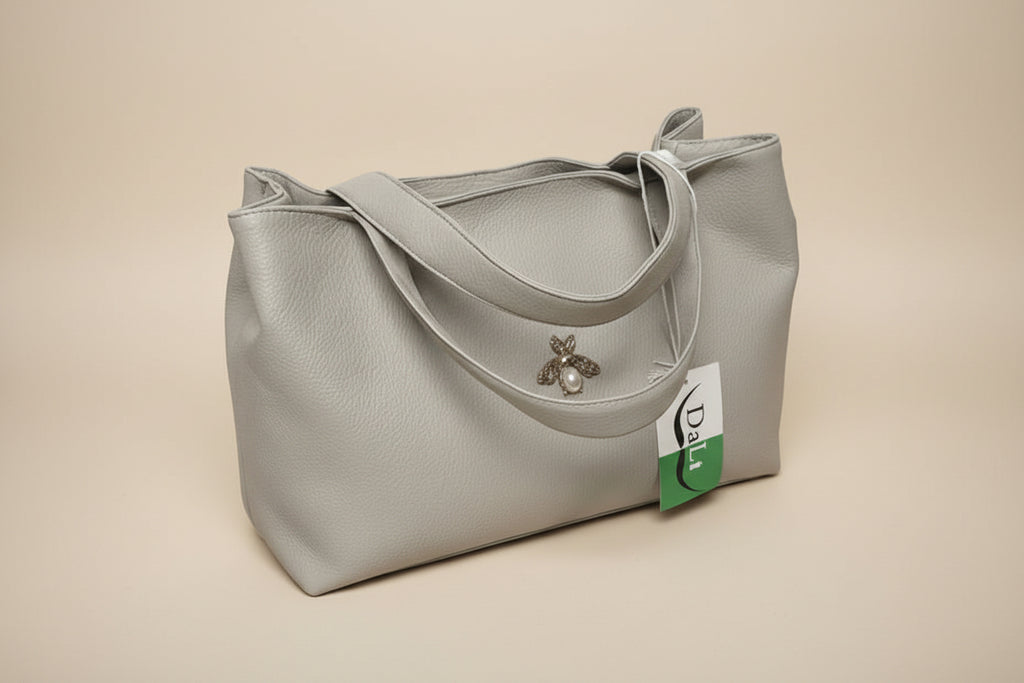 Gray handbag with a bee charm on a light gray background