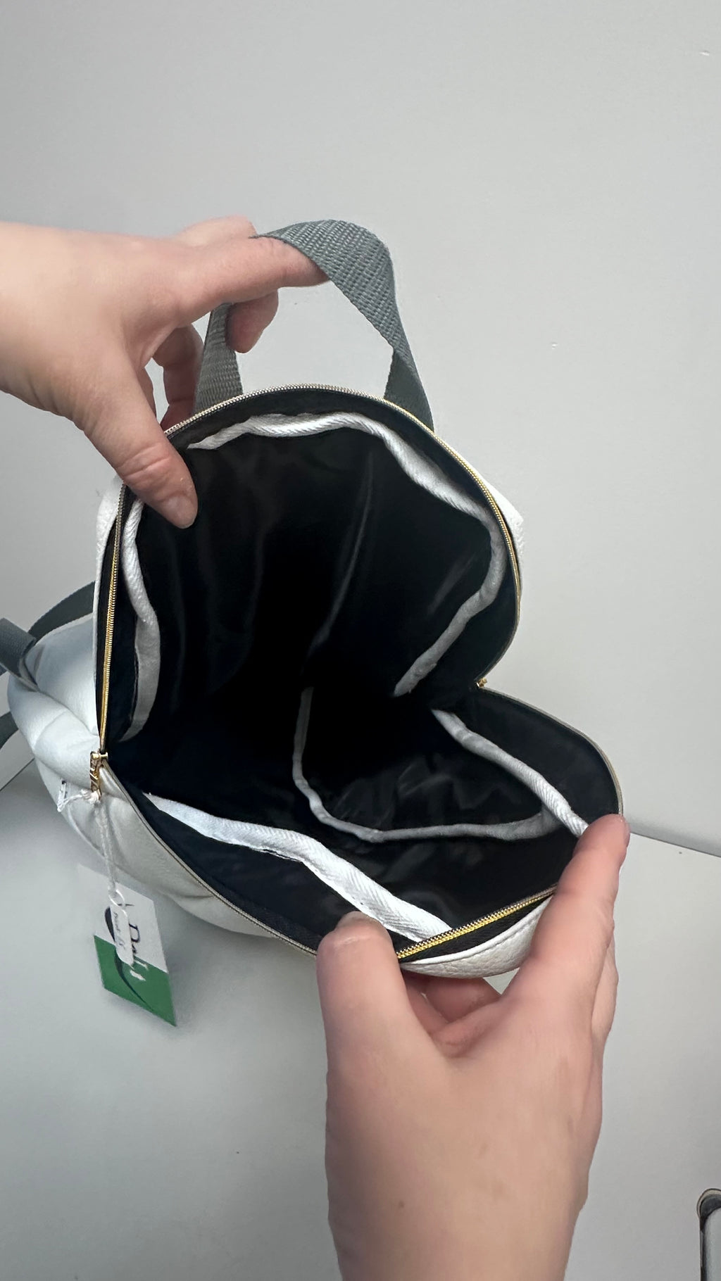 Person holding a black and white bag against a plain background