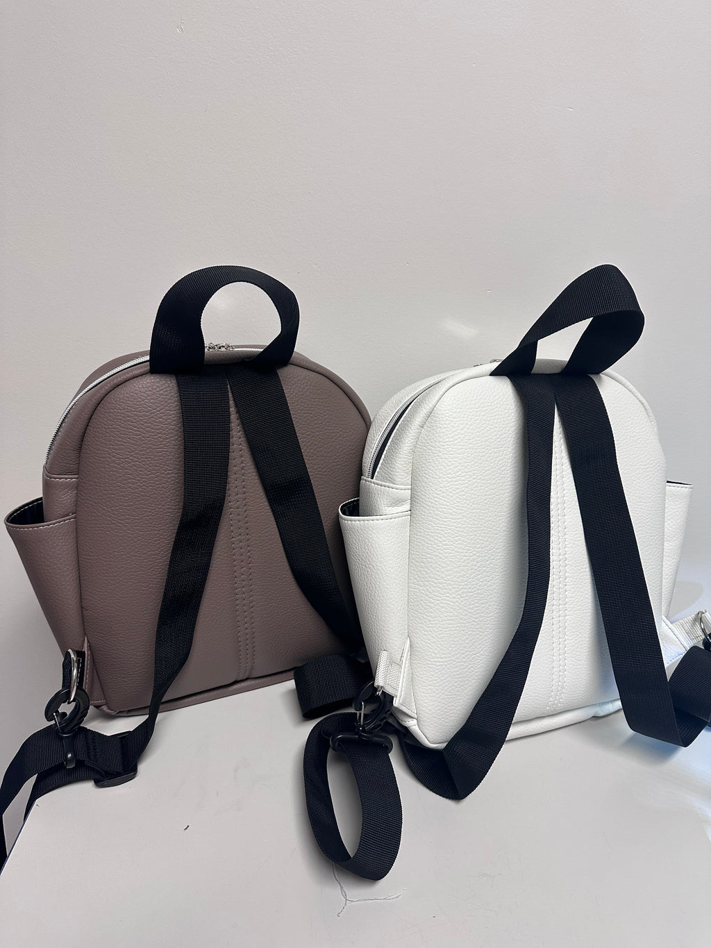 Two backpacks with black straps on a light gray background