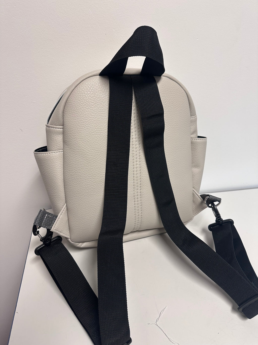 Light Grey backpack with black strap on a light gray background