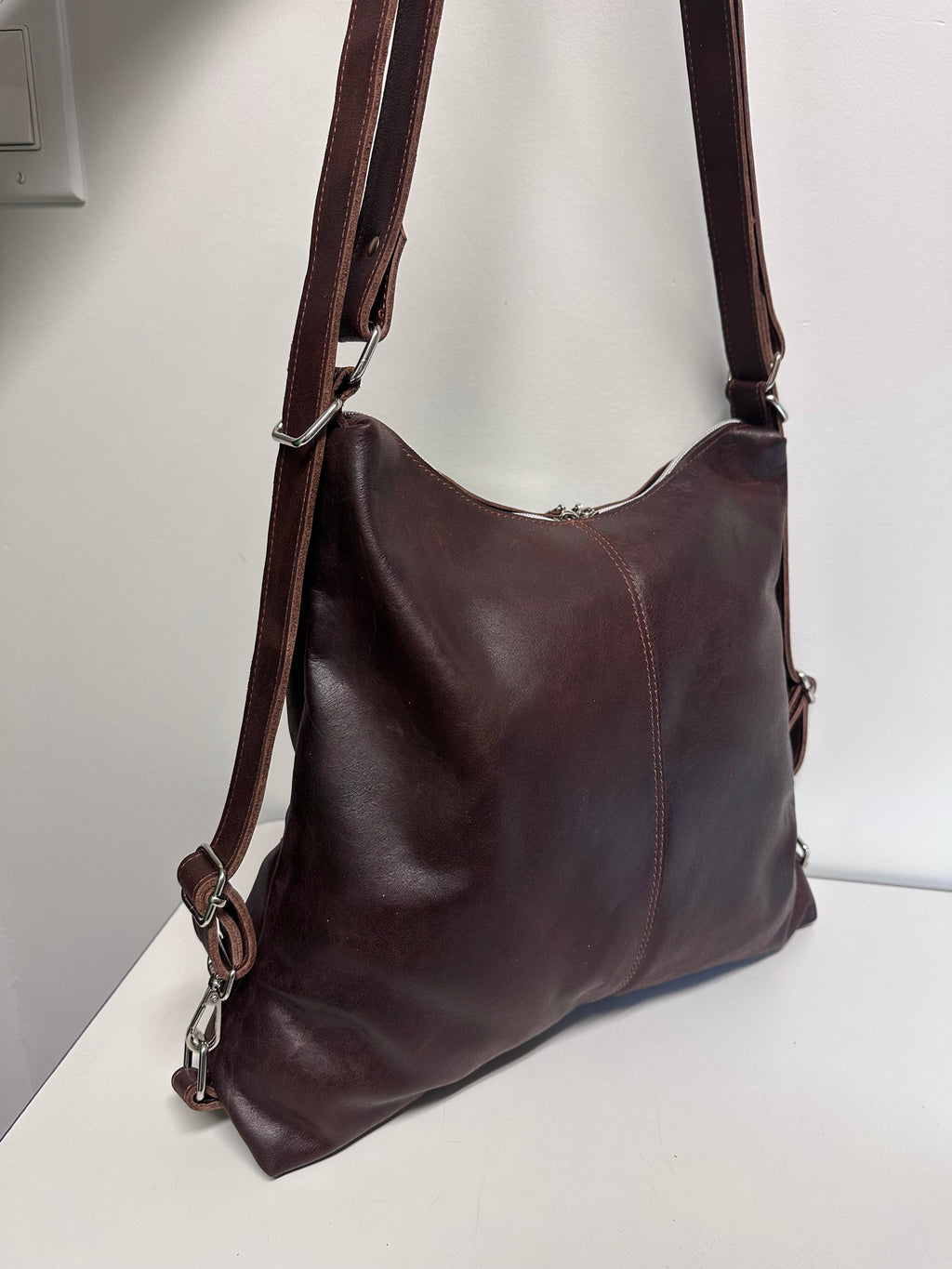 Brown leather handbag on a light gray surface with a white background