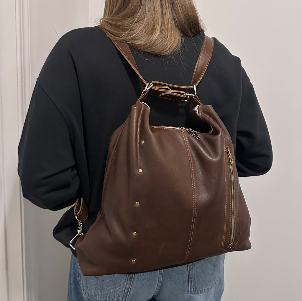 Person wearing a brown leather backpack with gold accents