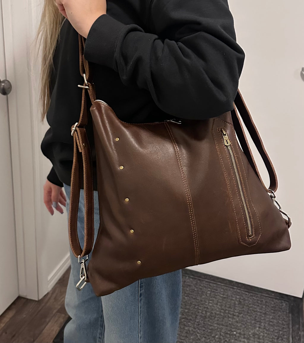 Person holding a brown leather handbag indoors
