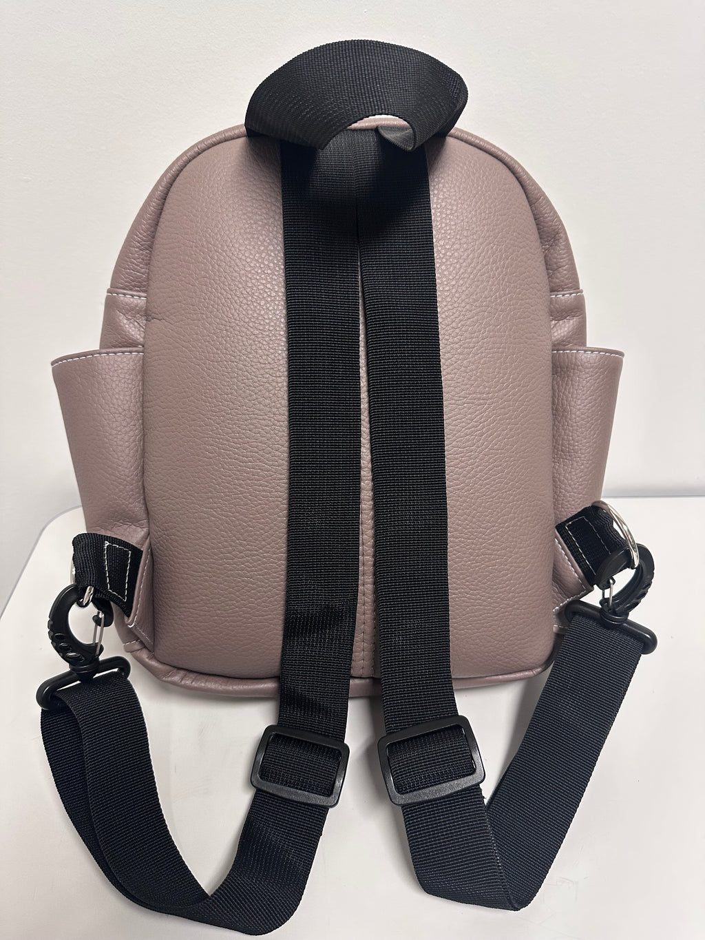 Tan backpack with black straps on a light gray background