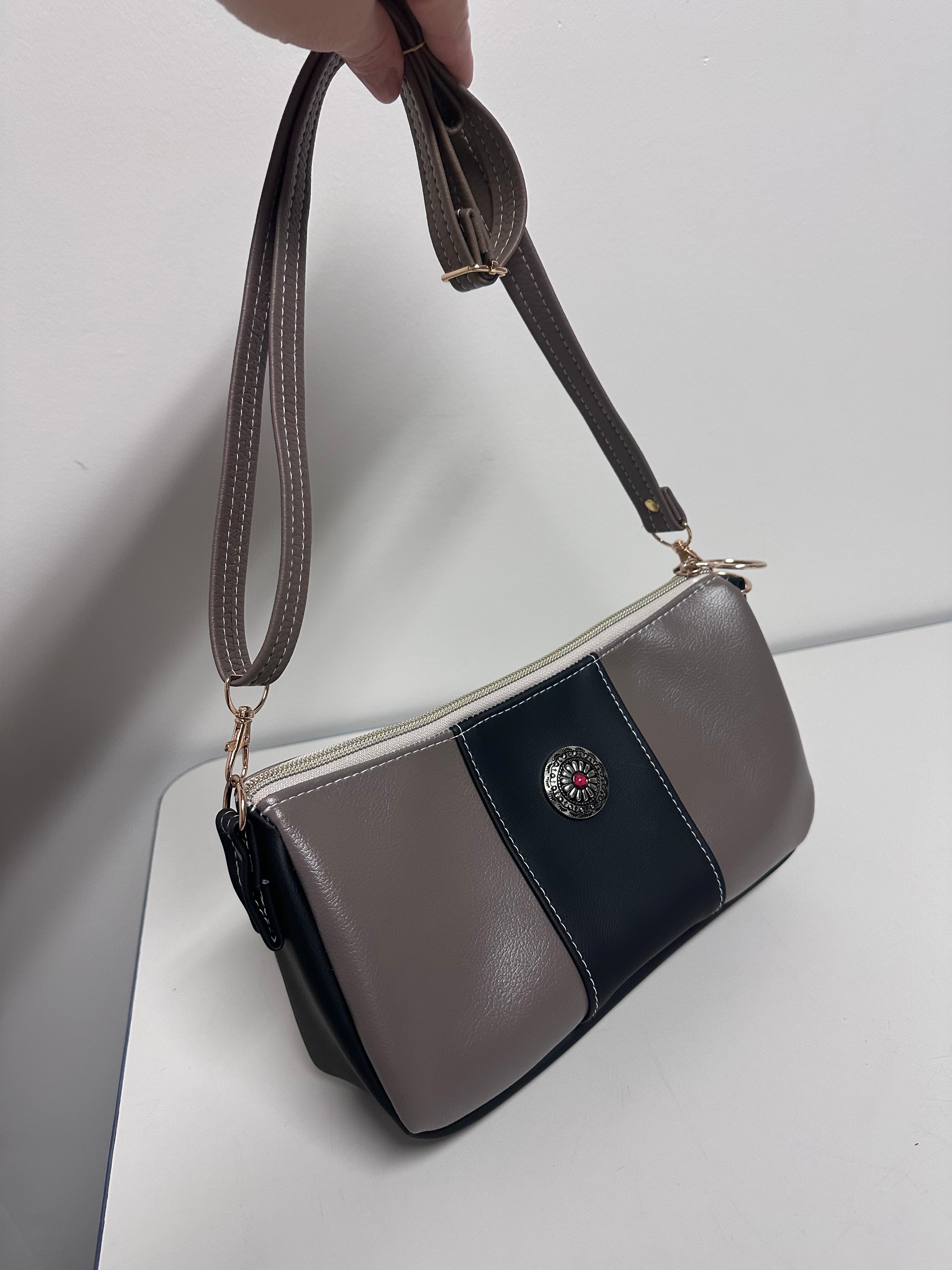 Tan and black handbag with a strap on a light gray background