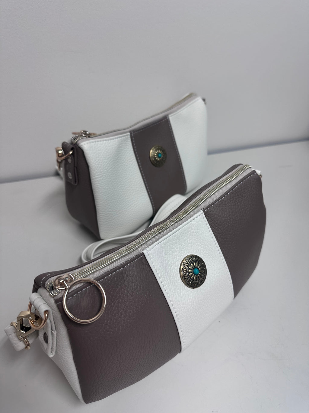 Two faux leather handbags, with decorative buttons on a light gray background.