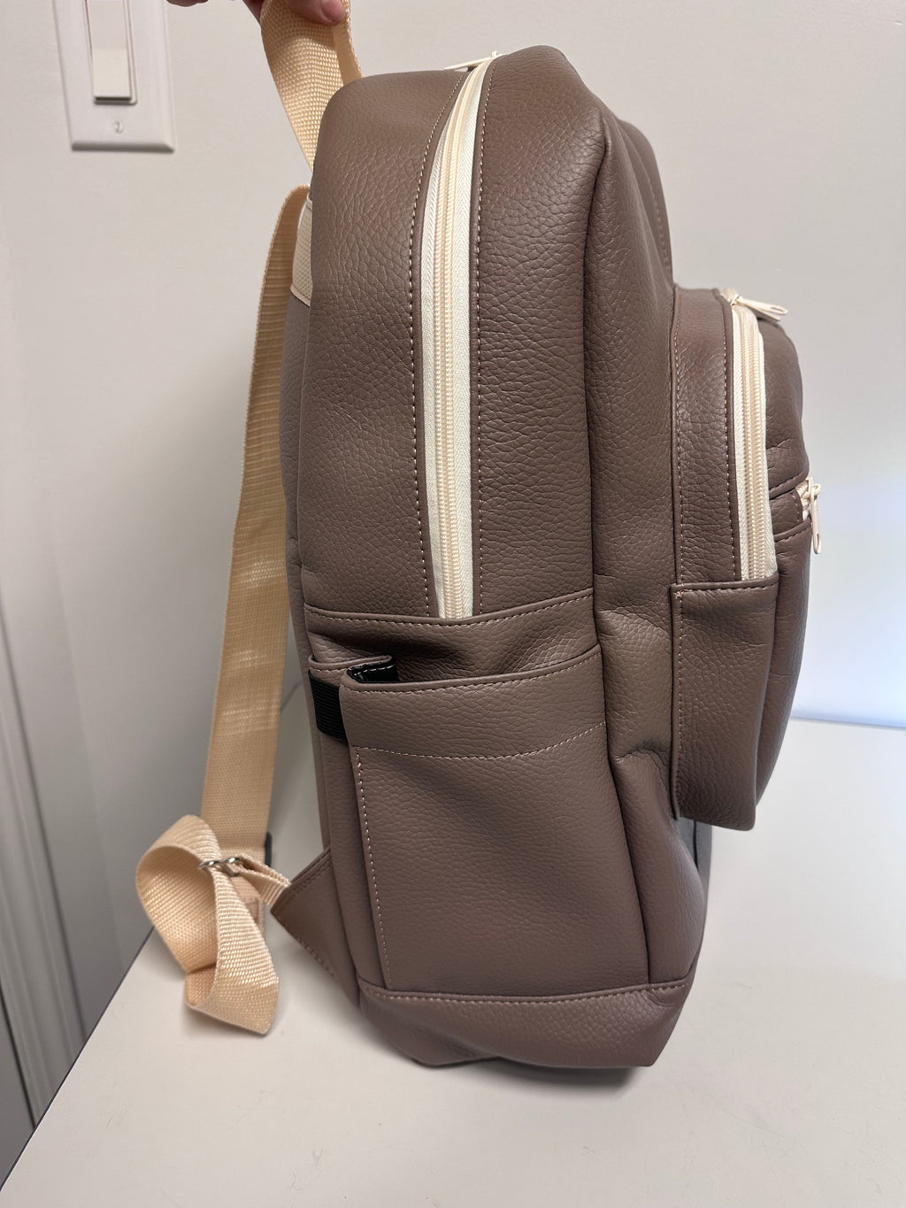 Brown faux leather bag with beige strap on a light gray background