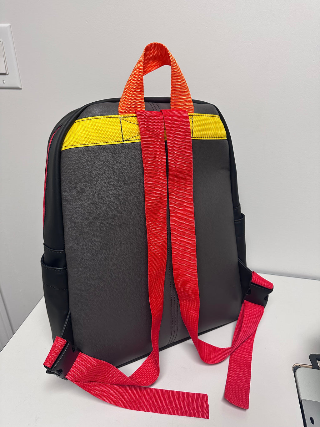 Black bag with colorful straps on a light gray background