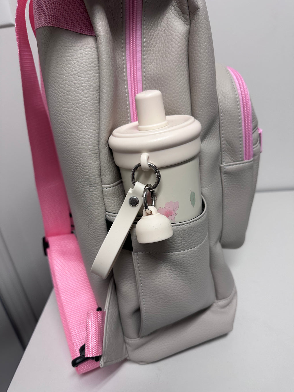 Gray bag with pink accents and a white handle on a light gray background