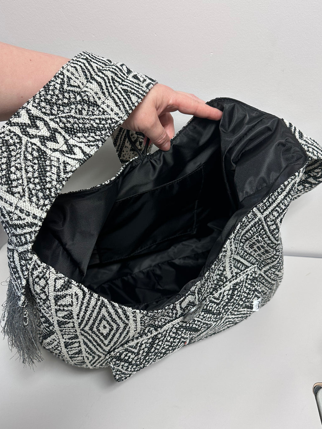Person holding a black and white patterned bag with a plain background