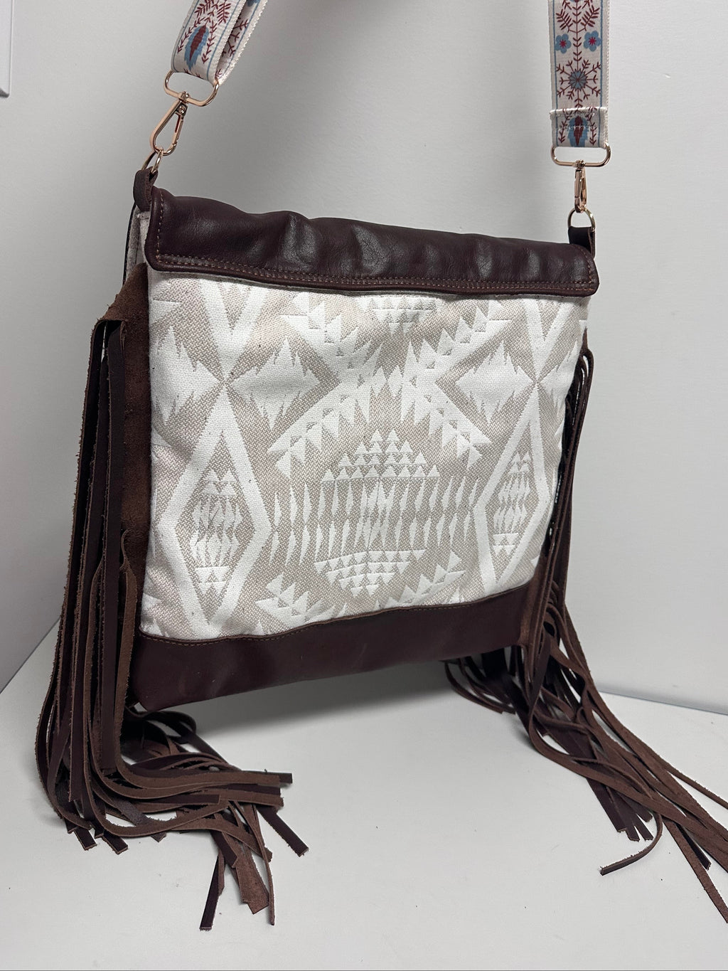 Handbag with patterned strap and fringe on a light background