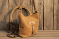 Brown leather handbag with a tassel on a wooden background